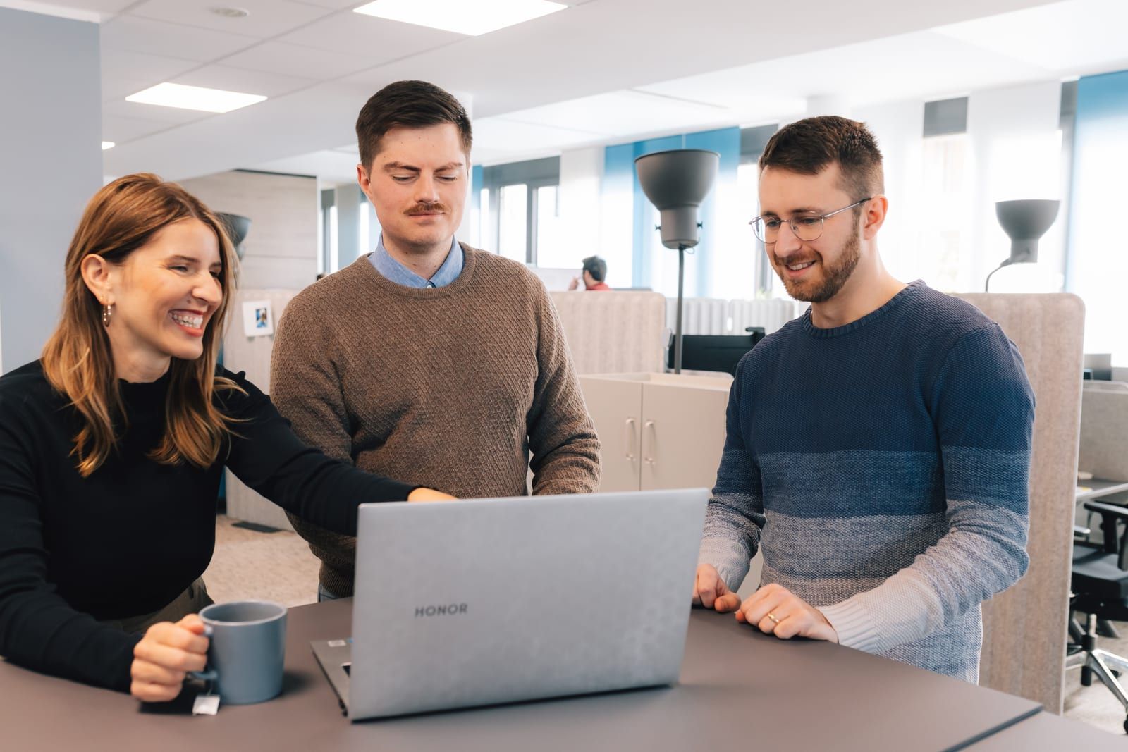 Das Team der Idana AG arbeitet gemeinsam am Laptop im Büro in Freiburg.