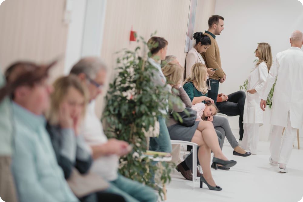 Volles Wartezimmer einer Arztpraxis, Patientinnen und Patienten warten sitzend und stehend